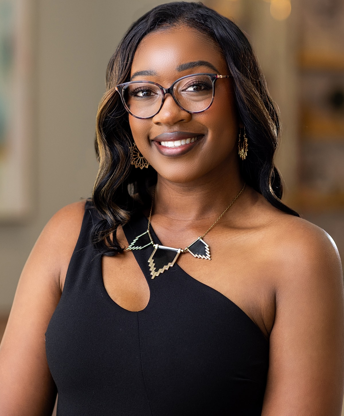Woman in black scrubs, smiling in hallway.