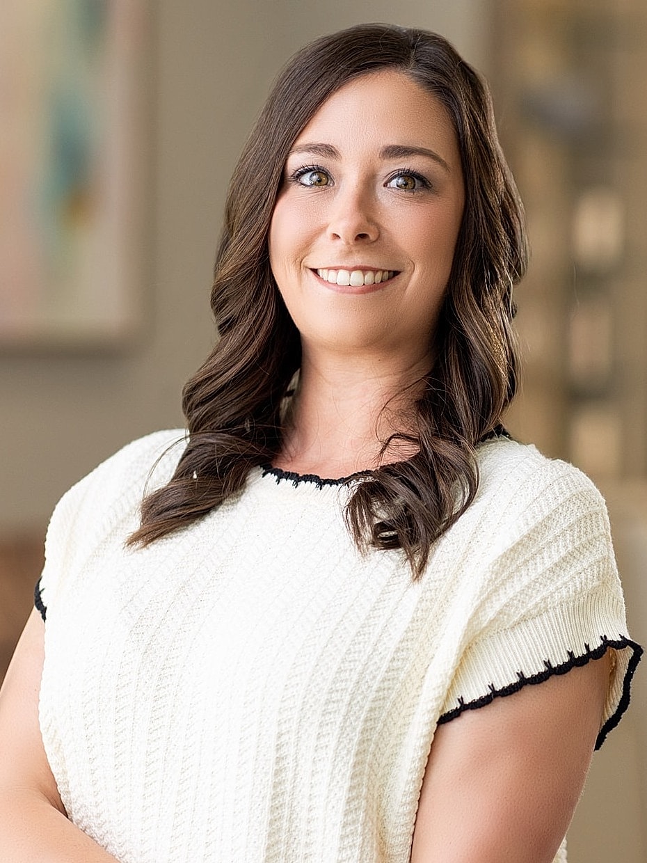 Woman in black scrubs, smiling in hallway.