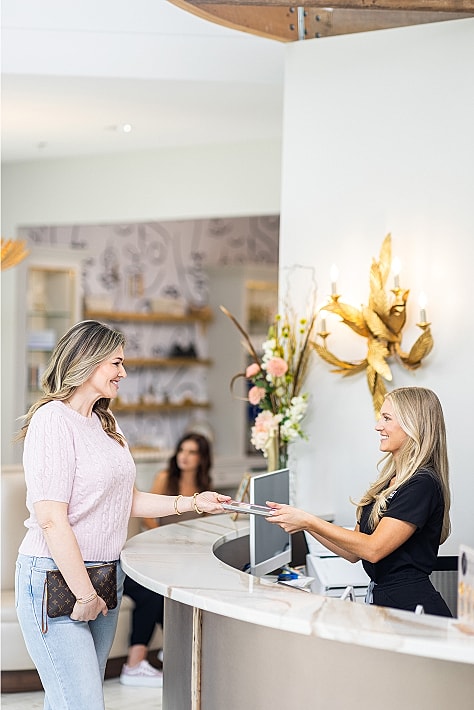 Woman checking in at a receptionist desk.