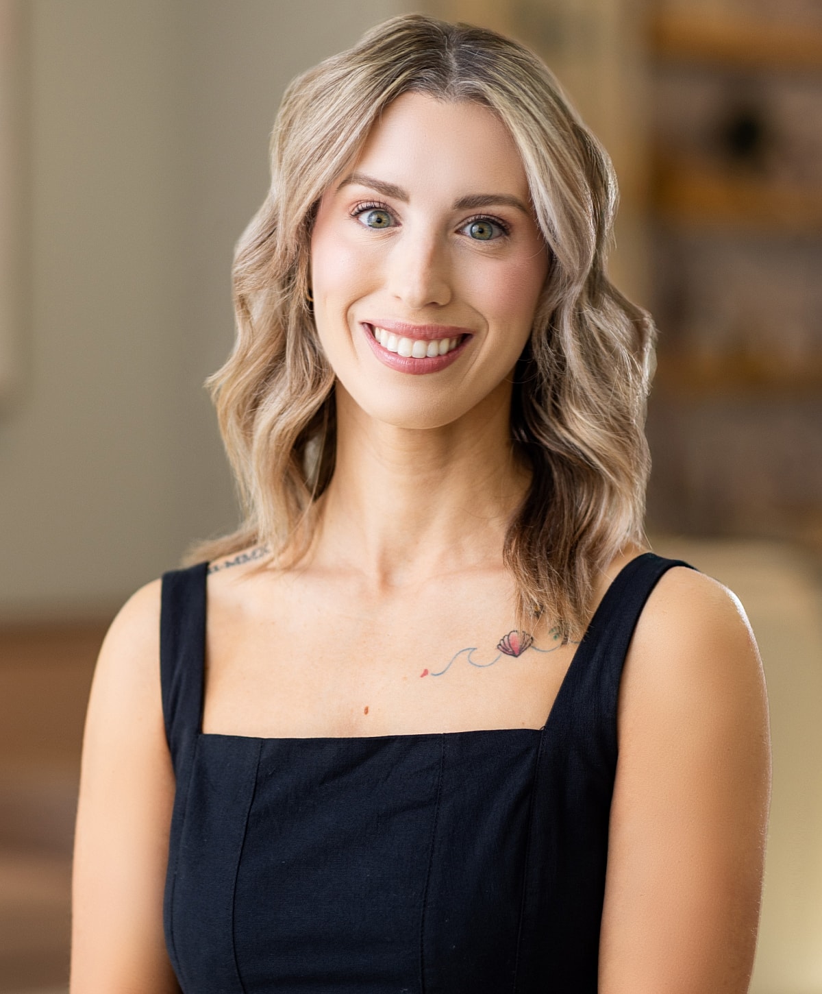 Smiling woman with shoulder-length hair and tattoo.