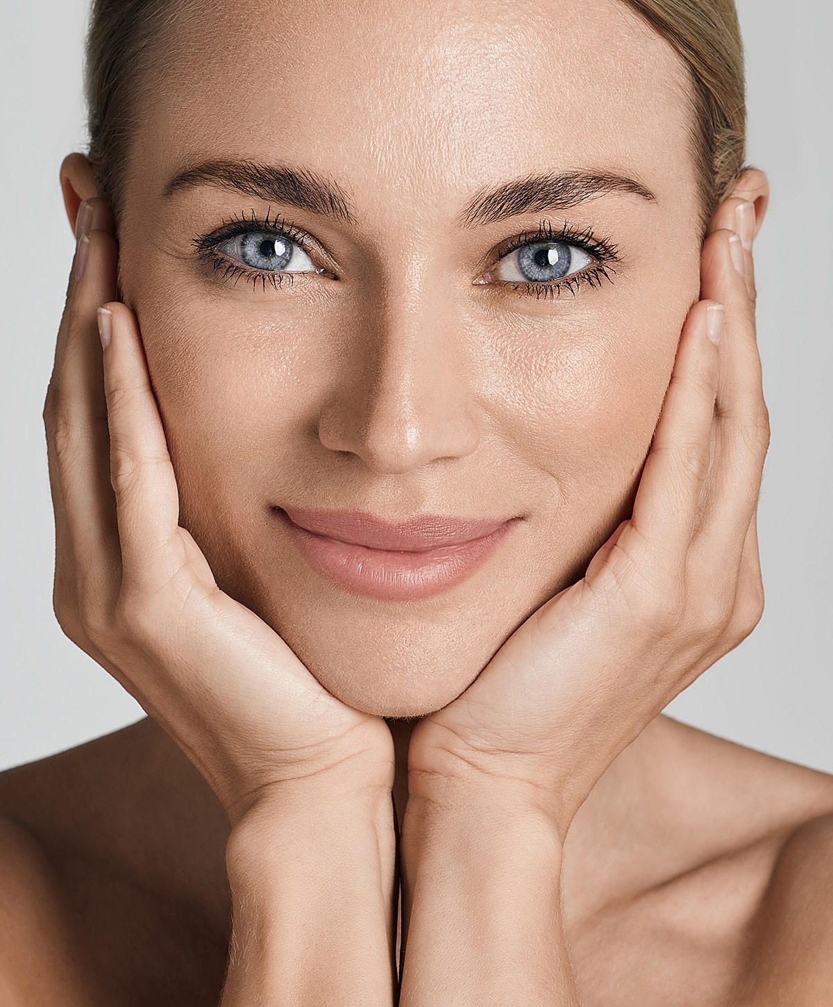 Smiling woman with curly hair and closed eyes.
