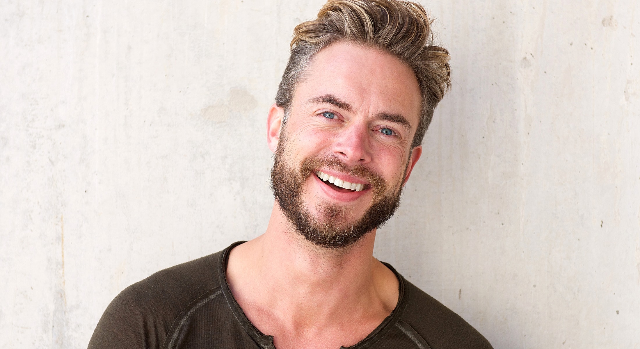 Man thoughtfully touching his chin, neutral background.